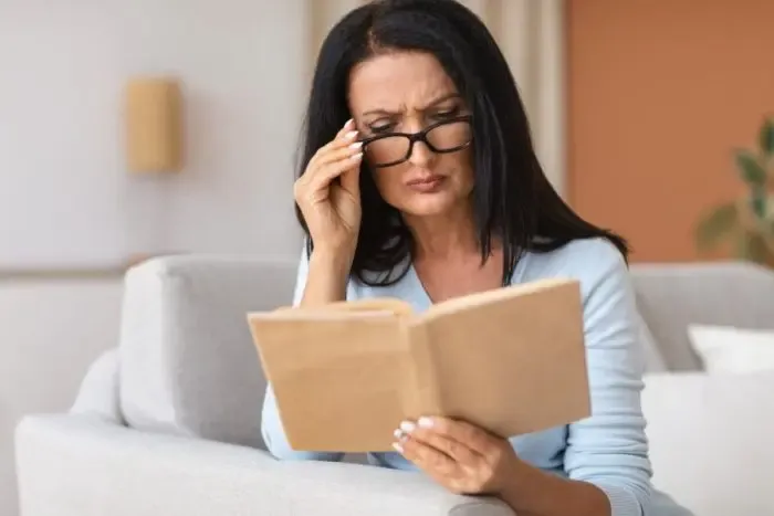 Femme astigmate lisant un livre, illustrant la correction visuelle nécessaire pour l’astigmatisme