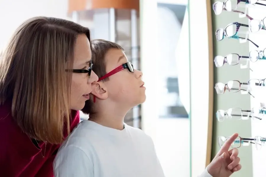 Enfant choisissant sa monture de lunettes avec sa maman, illustrant l’accompagnement familial dans le choix des lunettes