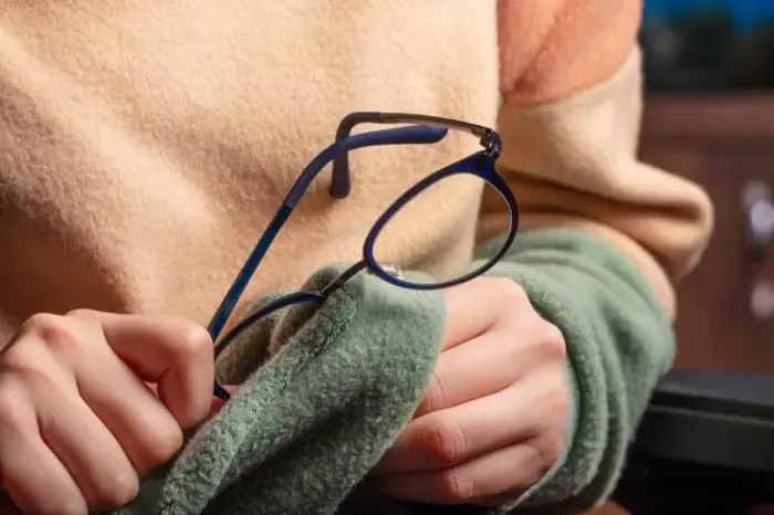 Personne nettoyant ses lunettes de vue pour améliorer la clarté et l'entretien des verres