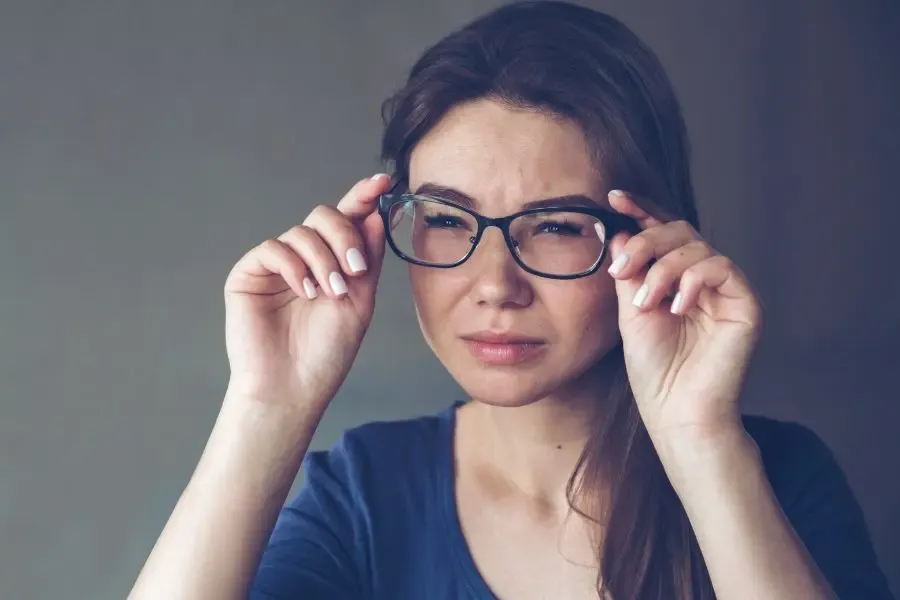 Femme astigmate portant une correction inadaptée, illustrant une vision floue et inconfortable