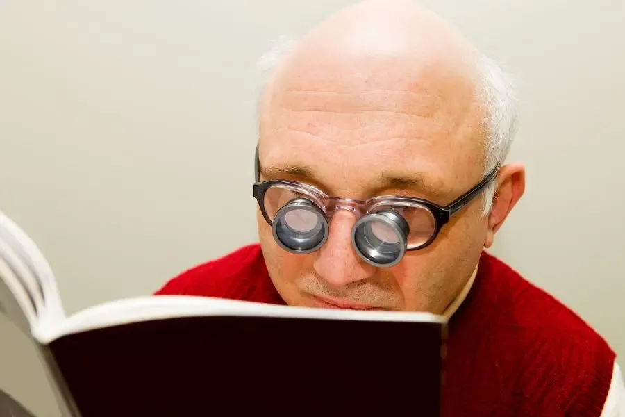Homme portant des lunettes adaptées à la DMLA pour faciliter la lecture