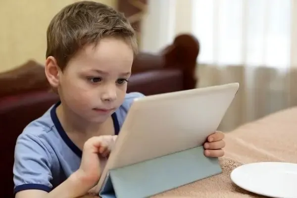 Enfant devant une tablette sans lunettes anti-lumière bleue