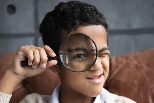 Enfant regardant à travers une loupe, illustrant la myopie et la santé visuelle chez les enfants