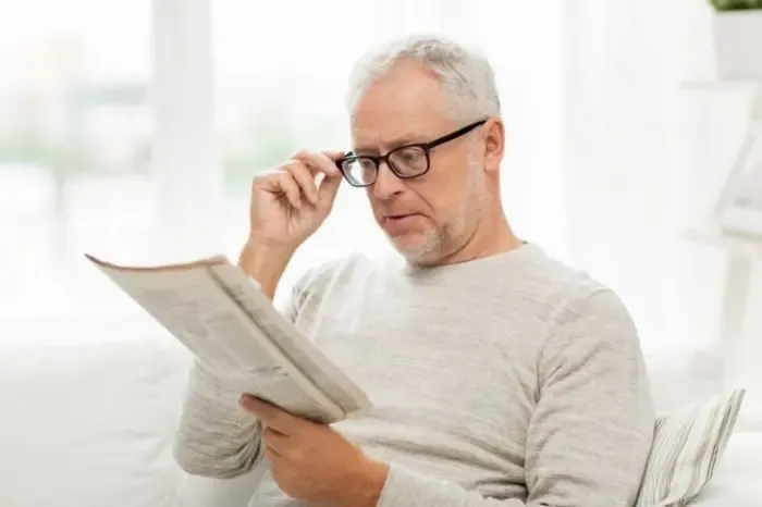 Homme lisant son journal avec des lunettes de vue, illustrant la lecture et la correction visuelle