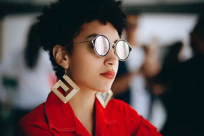 Femme portant des lunettes de soleil et de grandes boucles d’oreilles assorties, illustration d’un style audacieux et harmonieux