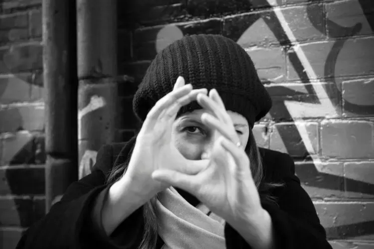 Femme regardant à travers ses mains comme un cadre de caméra pour symboliser la vision et le cadrage du regard
