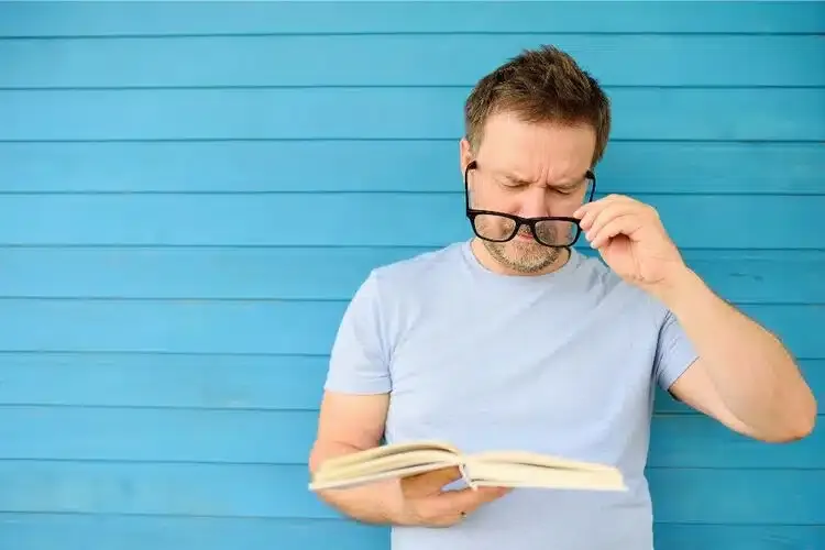 Homme presbyte portant des lunettes pour lire confortablement un livre