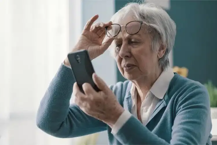 Femme myope retirant ses lunettes de vue pour lire plus facilement le contenu de son téléphone