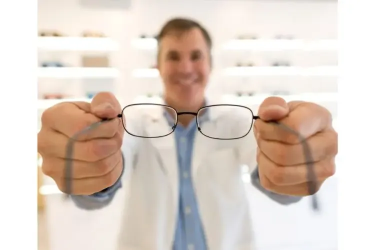 Opticien présentant une paire de lunettes à son client pour l’aider à choisir la monture adaptée